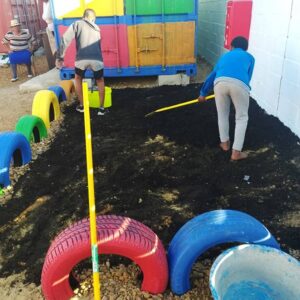 Working potting soil and fertiliser into the garden bed